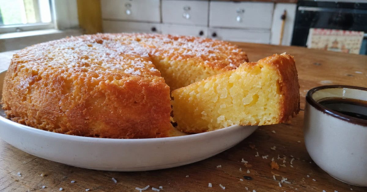 Nunca mais Faça Bolo de Mandioca seco: A Técnica que Muda tudo! 1 Fatia de bolo de mandioca úmido cortada sobre travessa de cerâmica branca com interior amarelo-dourado à mostra