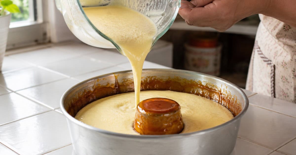 Pudim de Leite Furadinho! Este Ninguém Faz! 2 Mãos despejando creme de leite condensado e ovos na fôrma de pudim já caramelizada, em cozinha doméstica