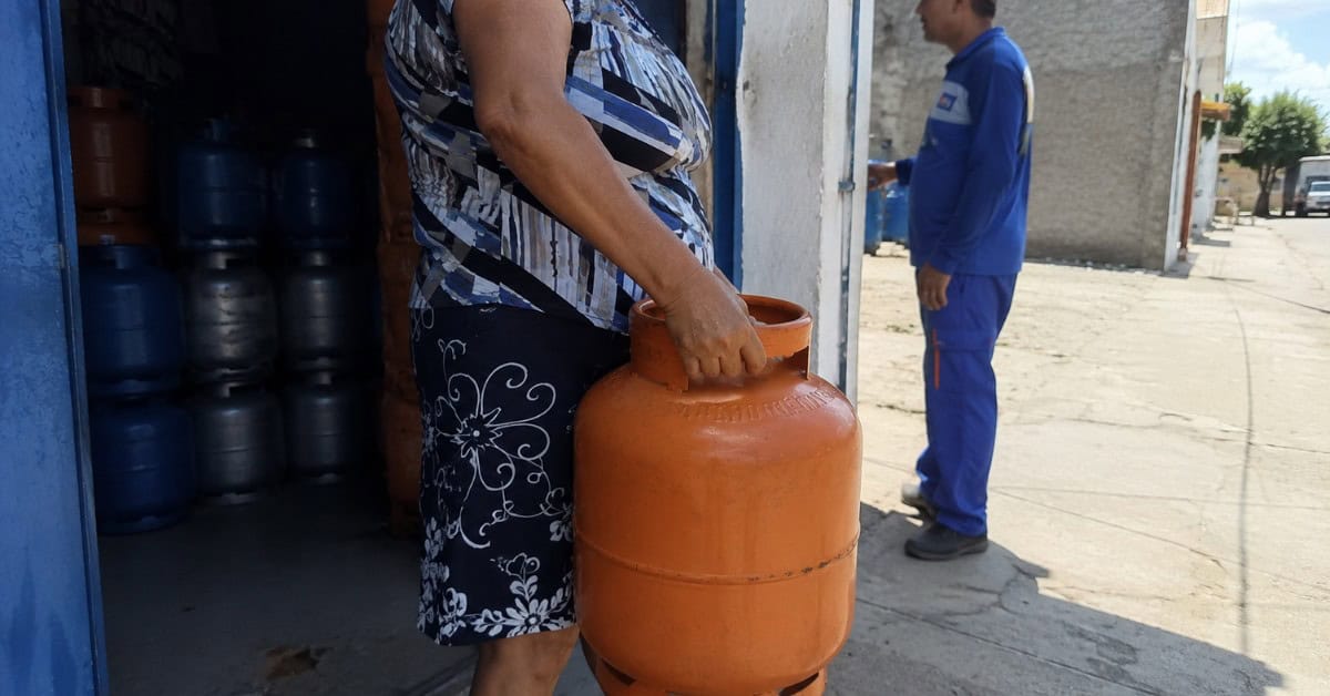 O Gás de Cozinha que Pesava no Bolso — e a Solução que Virou Lei 5 Mulher recebendo botijão de gás laranja de 13kg na porta de revenda credenciada com entregador ao fundo em bairro de periferia